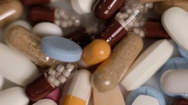 Yavaş çekim videosu beyaz arka plana yavaş çekimde düşen farklı tipte haplar. Çok renkli tabletler uçuyor. Masada çok güzel haplar var. Tıbbi görüntüler, sağlıklı yaşam tarzı