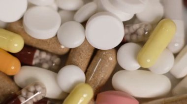 Yavaş çekim videosu beyaz arka plana yavaş çekimde düşen farklı tipte haplar. Çok renkli tabletler uçuyor. Masada çok güzel haplar var. Tıbbi görüntüler, sağlıklı yaşam tarzı