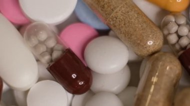 Yavaş çekim videosu beyaz arka plana yavaş çekimde düşen farklı tipte haplar. Çok renkli tabletler uçuyor. Masada çok güzel haplar var. Tıbbi görüntüler, sağlıklı yaşam tarzı