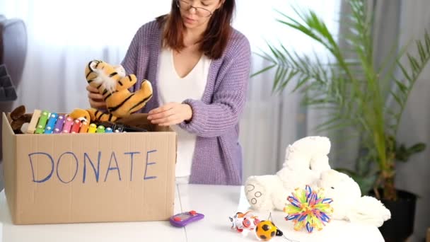 Caja de donaciones con juguetes para niños. mujer recoge juguetes para la caridad. Vídeo filmado . — Vídeos de Stock