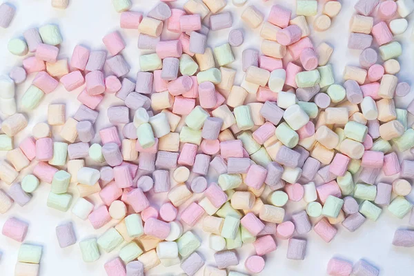 Вид сверху на пастельные конфеты маршмаллоу с некоторой скатертью на бледно-белом столе — стоковое фото