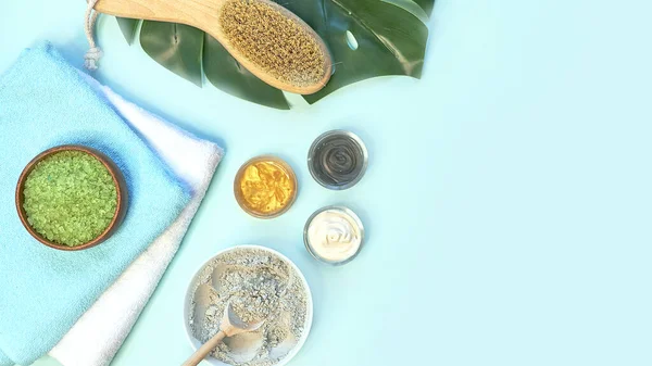 spa massage clay powder, face masks, bath salt, towel, shea butter on blue table background.