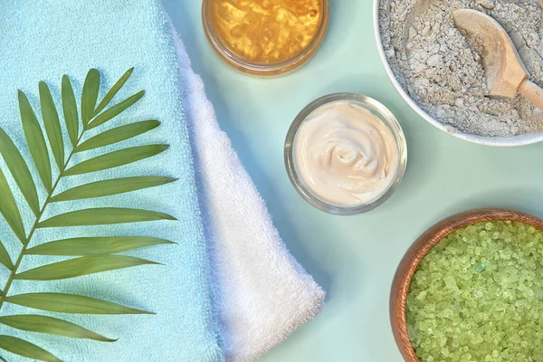 Spa massage lera pulver, ansiktsmasker, badsalt, handduk, sheasmör på blått bord bakgrund. — Stockfoto