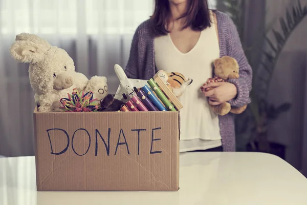 Donation box with children toys. woman collects toys for charity. — Stockfoto
