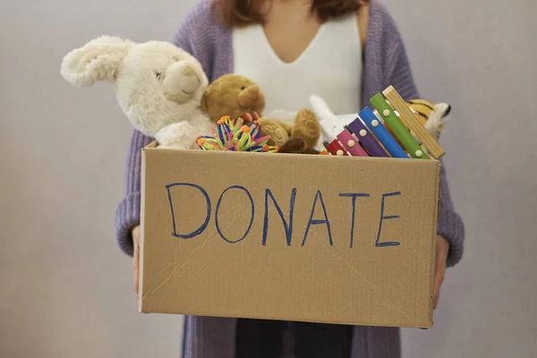 Caja de donaciones con juguetes para niños. mujer recoge juguetes para la caridad . — Foto de Stock