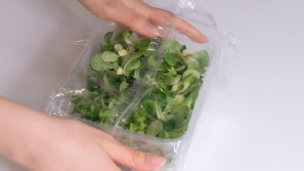 Mulher usando filme de comida para armazenamento de alimentos em uma mesa branca. Rolo de filme de polietileno transparente para produtos de embalagem. Vídeo em câmara lenta. Fechar — Vídeo de Stock