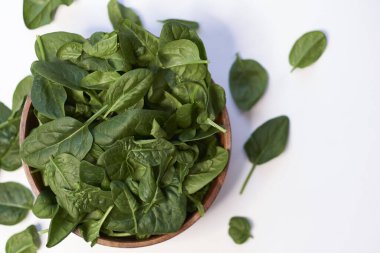 Fresh spinach in a wooden bowl isolated on white background top view photo