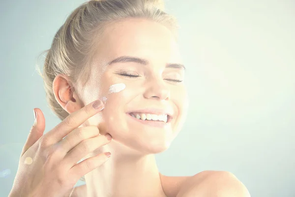 moisturizing summer skin care sunscreen. beautiful model applying cosmetic cream treatment on her face. rays of the sun illuminate the happy face of young women