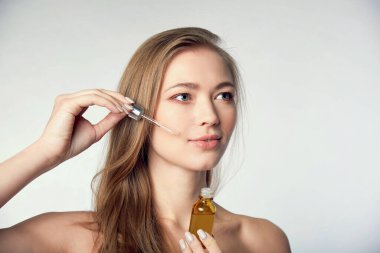Beyaz üzerinde deri serumu tedavisi uygulayan güzel bir model. Spa, cilt bakımı ve sağlık. Yakın çekim, kopyalanma alanı