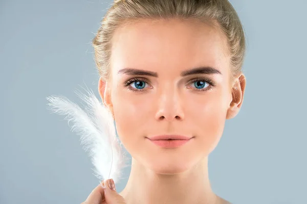 Retrato de menina atraente com olhos fechados. bela mulher com uma pena branca perto de seu rosto. Concepção do cuidado da pele da cara e do corpo, pele brilhante limpa fresca . — Fotografia de Stock