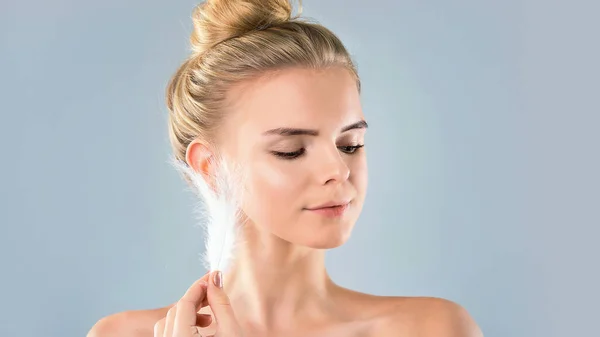 Retrato de chica atractiva con los ojos cerrados. hermosa mujer con una pluma blanca cerca de su cara. Concepto de cuidado de la piel de la cara y el cuerpo, piel brillante limpia fresca — Foto de Stock