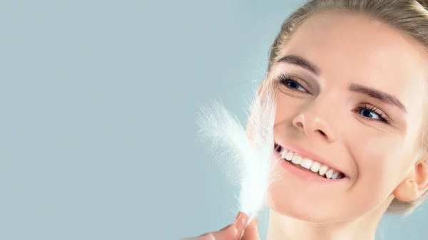 Retrato de chica atractiva con los ojos cerrados. hermosa mujer con una pluma blanca cerca de su cara. Concepto de cuidado de la piel de la cara y el cuerpo, piel brillante limpia fresca — Foto de Stock