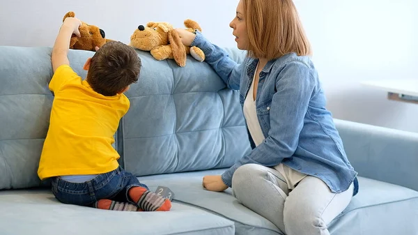 Мать и сын играют с игрушкой на диване. Веселитесь вместе. Мама пытается связаться со своим гиперактивным сыном — стоковое фото