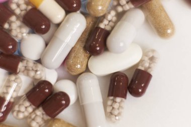 Beyaz arka plana yavaş çekimde düşen farklı türde haplar. Çok renkli tabletler uçuyor. Masada çok güzel haplar var. tıbbi