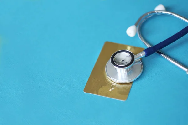 Stethoscope on Mock up Credit Card with number on cardholder in hospital desk. Health insurance and cost of care, self-care during illness using payments card for medicals service. Soft focus