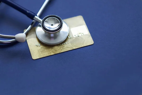 Stethoscope on Mock up Credit Card with number on cardholder in hospital desk. Health insurance and cost of care, self-care during illness using payments card for medicals service. Soft focus