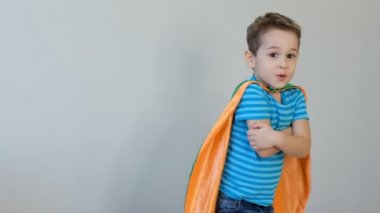 Süper kahraman kostümü giymiş bir çocuğun portresi elleriyle kendine sarılıyor. Başarı kavramı. Mutlu çocukluk. 4k video