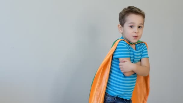 スーパーヒーローの衣装を着た少年の肖像画は彼の手で自分自身を抱きます。成功の概念。幸せな子供時代。4kビデオ — ストック動画