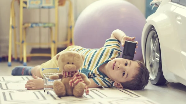 Маленький мальчик играет один в детской комнате и использует карту смарт-дома, чтобы слушать сказки . — стоковое фото
