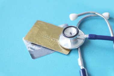Stetoskop, Mock Up Credit Card 'da. Hastane masasında kart sahibinin numarası var. Sağlık sigortası ve bakım masrafları, hastalık sırasında sağlık hizmeti için ödeme kartı kullanmak. Yumuşak odak