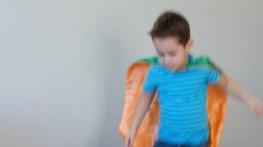 Süper kahraman kostümlü, yatakta zıplayan güçlü bir çocuğun portresi. Başarı kavramı. Mutlu çocukluk. 4k video