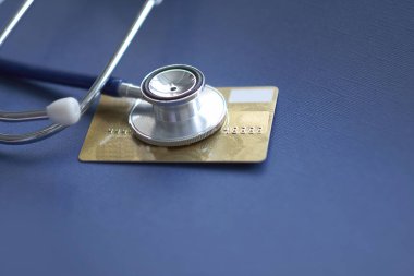 Stetoskop, Mock Up Credit Card 'da. Hastane masasında kart sahibinin numarası var. Sağlık sigortası ve bakım masrafları, hastalık sırasında sağlık hizmeti için ödeme kartı kullanmak. Yumuşak odak