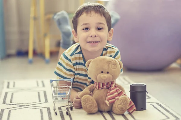 Liten pojke leker ensam i ett barnrum och använder ett smart hus kort för att lyssna på sagor. — Stockfoto