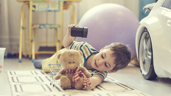 Little boy plays alone in a childrens room and uses a smart house card to listen to fairy tales. — Stock Photo, Image