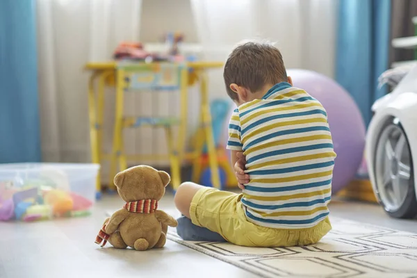 Trieste jongen zit op de vloer van de kinderkamer. eenzaam kind mist thuis — Stockfoto