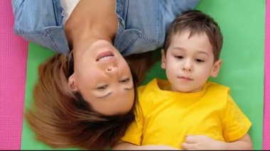 Anne ve oğlu evde yerde yatıyor. Oğluyla mutlu bir annenin video portresi..
