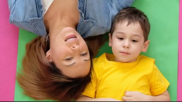 妈妈和儿子躺在家里的地板上。一个快乐的母亲和她的儿子的视频肖像. — 图库视频影像
