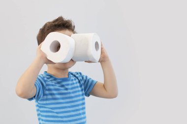 Aktif çocuk tuvalet kağıdıyla retro filtrede oynuyor, çocuk tuvalet kağıdına bakıyor, çocuk iki beyaz peçete tutuyor, tuvalet kağıdına dürbün gibi bakıyor.
