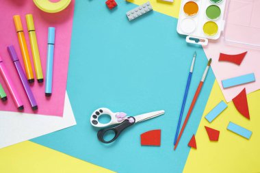Okul malzemeleri, sarı arka planda kırtasiye malzemesi - manşet için yer. Çocuk kalemle çizmeye ve renkli kağıt uygulamaya hazır. Üst görünüm.