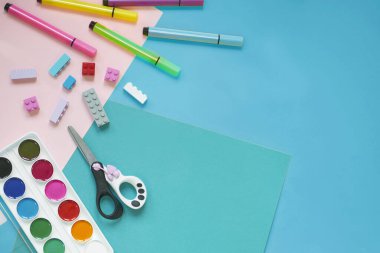 Okul malzemeleri, sarı arka planda kırtasiye malzemesi - manşet için yer. Çocuk kalemle çizmeye ve renkli kağıt uygulamaya hazır. Üst görünüm.