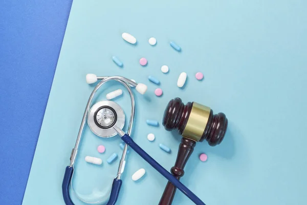 Brązowy młotek i stetoskop medyczny na niebieskim tle. symbol zdjęcie do spartaczenia i błąd medyczny — Zdjęcie stockowe