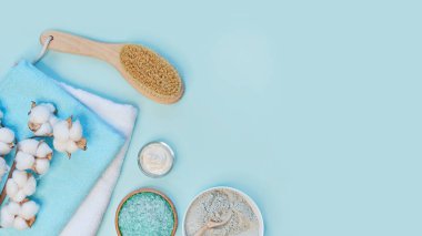 Masaj kil tozu, yüz maskeleri, banyo tuzu, havlu, mavili tereyağı mavi masa arkasında..
