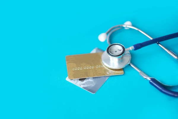 Stethoscope on Mock up Credit Card with number on cardholder in hospital desk. Health insurance and cost of care, self-care during illness using payments card for medicals service. Soft focus