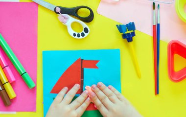 Okul malzemeleri, sarı arka planda kırtasiye malzemesi - manşet için yer. Çocuk kalemle çizmeye ve renkli kağıt uygulamaya hazır. Üst görünüm.