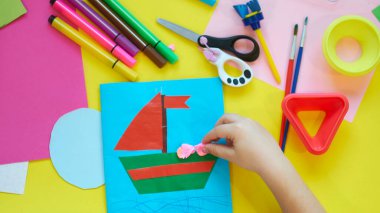 Okul malzemeleri, sarı arka planda kırtasiye malzemesi - manşet için yer. Çocuk kalemle çizmeye ve renkli kağıt uygulamaya hazır. Üst görünüm.