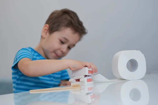 Kisfiú játszik fogászati állkapocs elrendezése és WC-papír. — Stock Fotó