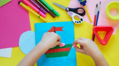 Okul malzemeleri, sarı arka planda kırtasiye malzemesi - manşet için yer. Çocuk kalemle çizmeye ve renkli kağıt uygulamaya hazır. Üst görünüm.