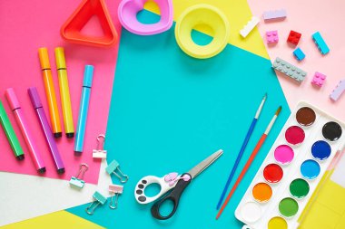 Okul malzemeleri, mavi arka planda kırtasiye malzemesi - manşet için yer. Çocuk kalemle çizmeye ve renkli kağıt uygulamaya hazır. Üst görünüm.