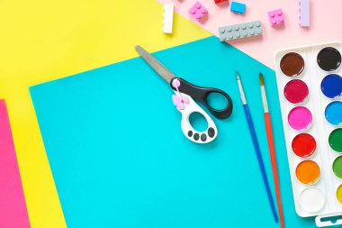 Okul malzemeleri, sarı arka planda kırtasiye malzemesi - manşet için yer. Çocuk kalemle çizmeye ve renkli kağıt uygulamaya hazır. Üst görünüm.