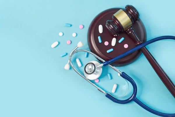Mazo marrón y un estetoscopio médico sobre fondo azul. símbolo de la foto para la confusión y el error médico . — Foto de Stock