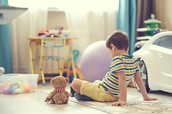 Грустный мальчик сидит на полу детской. одинокий ребенок скучает по дому — стоковое фото