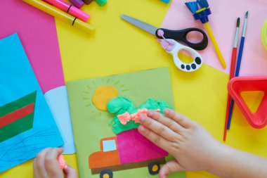 Okul malzemeleri, sarı arka planda kırtasiye malzemesi - manşet için yer. Çocuk kalemle çizmeye ve renkli kağıt uygulamaya hazır. Üst görünüm.