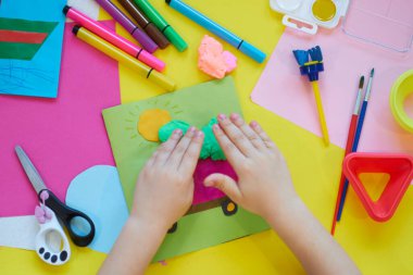 Okul malzemeleri, sarı arka planda kırtasiye malzemesi - manşet için yer. Çocuk kalemle çizmeye ve renkli kağıt uygulamaya hazır. Üst görünüm.