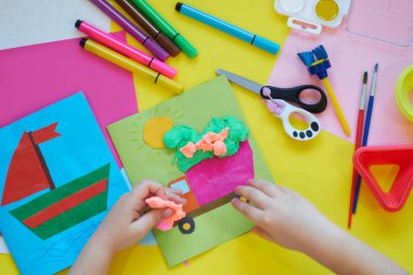 Okul malzemeleri, sarı arka planda kırtasiye malzemesi - manşet için yer. Çocuk kalemle çizmeye ve renkli kağıt uygulamaya hazır. Üst görünüm.