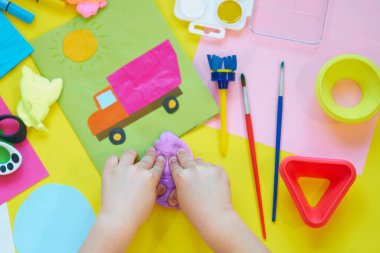 Okul malzemeleri, sarı arka planda kırtasiye malzemesi - manşet için yer. Çocuk kalemle çizmeye ve renkli kağıt uygulamaya hazır. Üst görünüm.