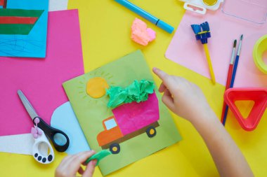 Okul malzemeleri, sarı arka planda kırtasiye malzemesi - manşet için yer. Çocuk kalemle çizmeye ve renkli kağıt uygulamaya hazır. Üst görünüm.